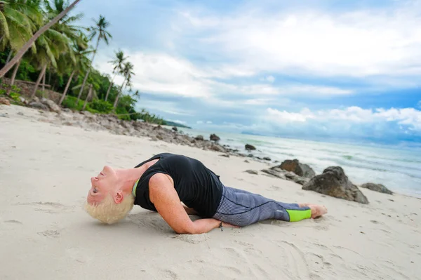 Güzel olgun yaşlı kadın bir ıssız tropikal beac Yoga yapıyor — Stok fotoğraf