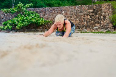 Güzel olgun yaşlı kadın bir ıssız tropikal beac Yoga yapıyor