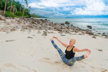 Güzel olgun yaşlı kadın bir ıssız tropikal beac Yoga yapıyor
