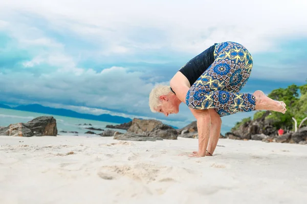 Güzel olgun yaşlı kadın bir ıssız tropikal beac Yoga yapıyor
