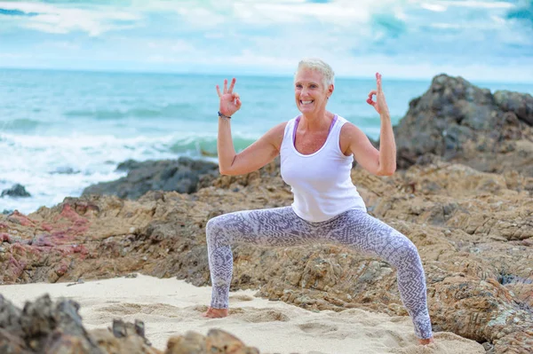 Beautiful mature aged woman doing yoga on a desert tropical beac — Stock Photo, Image