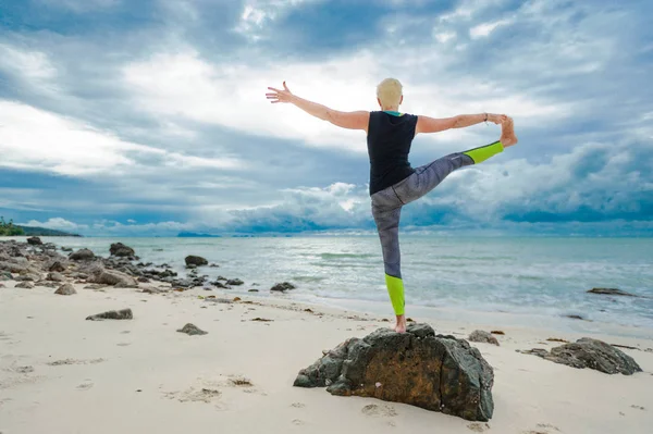 Güzel olgun yaşlı kadın bir ıssız tropikal beac Yoga yapıyor