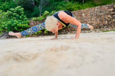 Güzel olgun yaşlı kadın bir ıssız tropikal beac Yoga yapıyor