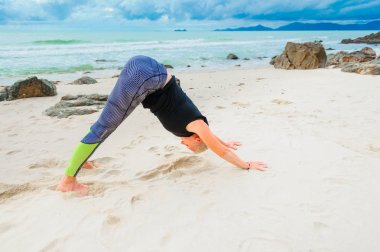 Güzel olgun yaşlı kadın bir ıssız tropikal beac Yoga yapıyor