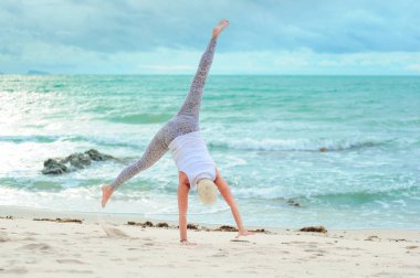 Güzel olgun yaşlı kadın bir ıssız tropikal beac Yoga yapıyor
