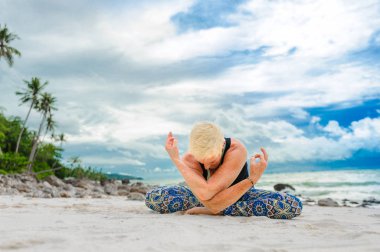 Güzel olgun yaşlı kadın bir ıssız tropikal beac Yoga yapıyor