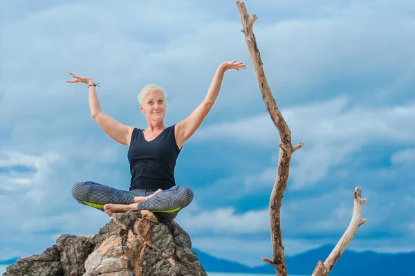Beautiful mature aged woman doing yoga on a desert tropical beac — Stock Photo, Image