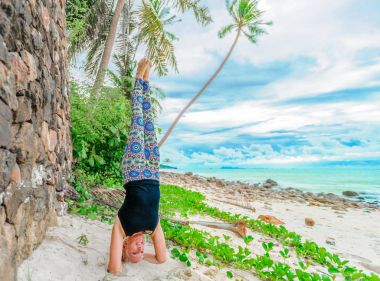 Güzel olgun yaşlı kadın bir ıssız tropikal beac Yoga yapıyor
