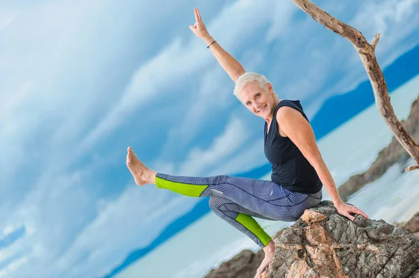 Güzel olgun yaşlı kadın bir ıssız tropikal beac Yoga yapıyor