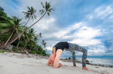 Güzel olgun yaşlı kadın bir ıssız tropikal beac Yoga yapıyor