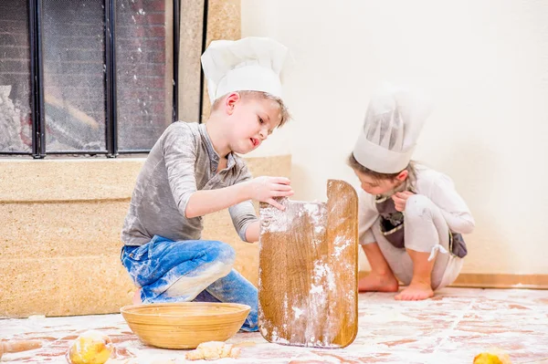 Dos hermanos - niño y niña - en sombreros de chef cerca de la chimenea — Foto de Stock