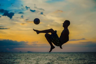 Bir topu tekmeleme. Bir adam bir plajda silüeti