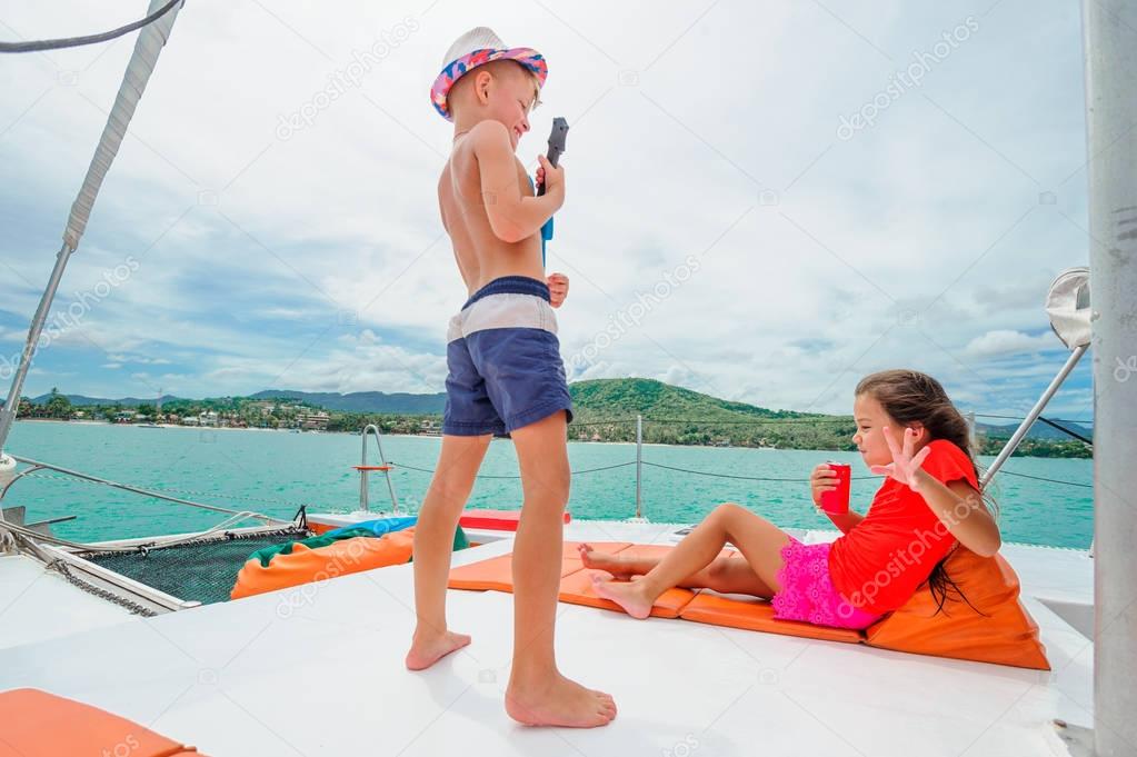 Cute kids on a boat trip. Boy is playing a toy guitar for his be