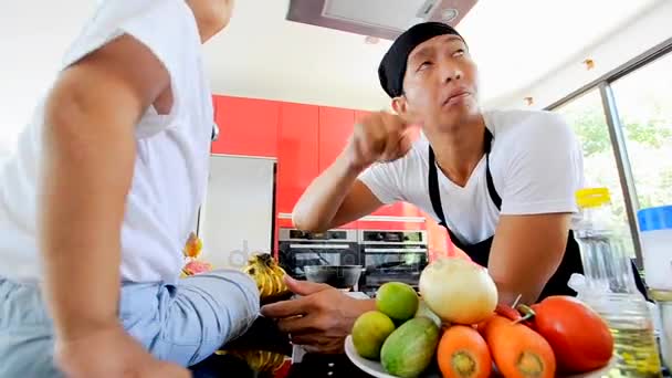 Приватні тайський шеф-кухар приготування їжі, його маленький син в капелюсі шеф-кухаря неподалік сидять на столі в сучасному стилі домашньої кухні. Хлопчик робить тайської кухні. — стокове відео