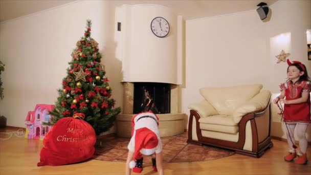 gute Neujahrsstimmung: Weihnachtsmann, Weihnachtsbaum, Geschenktüte, Kamin - festlich gekleidete Zweigenerationenfamilie feiert Winterurlaub, tanzt vor der Kamera, spielt Narr