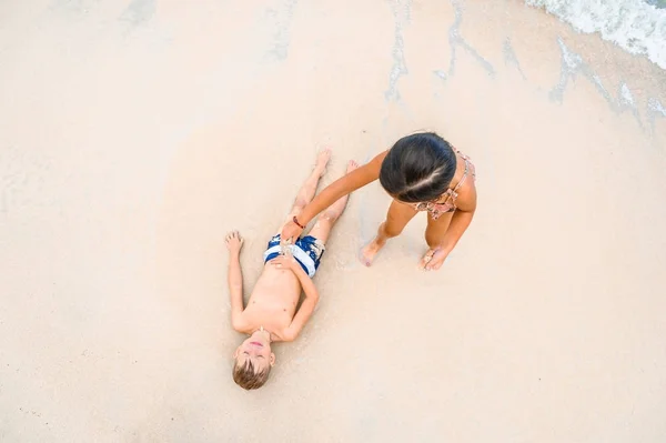 Két gyerek szórakozik a napsütéses trópusi tengerparton — Stock Fotó
