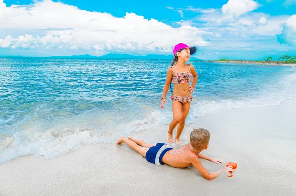 Due bambini si divertono sulla soleggiata spiaggia tropicale — Foto Stock