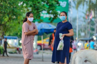 Koh Samui, Tayland - 30 Mart 2020: gıda pazarında hamile bir kadın arkadaşıyla konuşuyor. Her iki bayan da Covid-19 'un yayılmasını önlemek için maske takıyor.