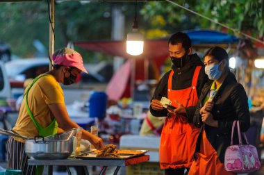 Koh Samui, Tayland - 30 Mart 2020: Covid-19 ile ilişkili tehlikelere rağmen sokak satıcıları çalışmaya devam ediyor. Önlemler alınıyor: satıcıların ve müşterilerinin maskeleri, raflarda el dezenfektanı