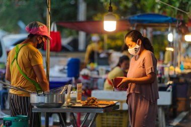 Koh Samui, Tayland - 30 Mart 2020: Covid-19 ile ilişkili tehlikelere rağmen sokak satıcıları çalışmaya devam ediyor. Önlemler alınıyor: satıcıların ve müşterilerinin maskeleri, raflarda el dezenfektanı