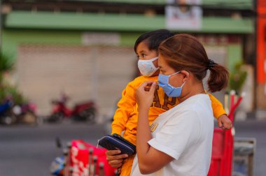 Koh Samui, Tayland - 30 Mart 2020: Küçük çocuk ve annesi yiyecek bulmak için yerel bir markete geldiler. Her ikisi de Coronavirus COVID-19 'un yayılmasını önlemek için maske takıyor..