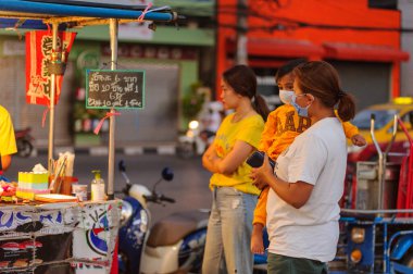 Koh Samui, Tayland - 30 Mart 2020: sokak satıcıları çalışmaya devam ediyor, küçük çocuk ailesiyle yiyecek almaya geliyor. Önlemler alındı: el dezenfektanı, satıcıların maskeleri ve onların küçük müşterileri ve anneleri..