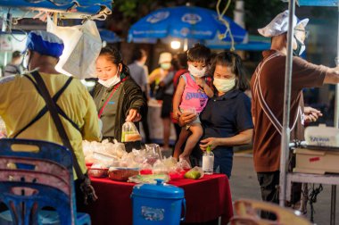 Koh Samui, Tayland - 30 Mart 2020: sokak satıcıları çalışmaya devam ediyor, küçük çocuk ailesiyle yiyecek almaya geliyor. Önlemler alındı: el dezenfektanı, satıcıların maskeleri ve onların küçük müşterileri ve anneleri..