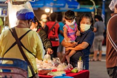 Koh Samui, Tayland - 30 Mart 2020: sokak satıcıları çalışmaya devam ediyor, küçük çocuk ailesiyle yiyecek almaya geliyor. Önlemler alındı: el dezenfektanı, satıcıların maskeleri ve onların küçük müşterileri ve anneleri..