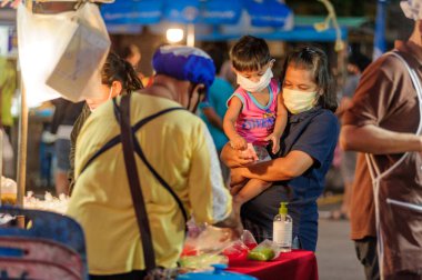 Koh Samui, Tayland - 30 Mart 2020: sokak satıcıları çalışmaya devam ediyor, küçük çocuk ailesiyle yiyecek almaya geliyor. Önlemler alındı: el dezenfektanı, satıcıların maskeleri ve onların küçük müşterileri ve anneleri..