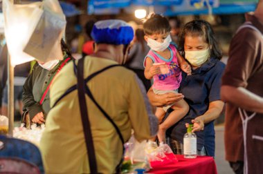 Koh Samui, Tayland - 30 Mart 2020: sokak satıcıları çalışmaya devam ediyor, küçük çocuk ailesiyle yiyecek almaya geliyor. Önlemler alındı: el dezenfektanı, satıcıların maskeleri ve onların küçük müşterileri ve anneleri..