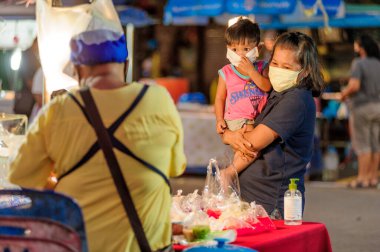 Koh Samui, Tayland - 30 Mart 2020: sokak satıcıları çalışmaya devam ediyor, küçük çocuk ailesiyle yiyecek almaya geliyor. Önlemler alındı: el dezenfektanı, satıcıların maskeleri ve onların küçük müşterileri ve anneleri..