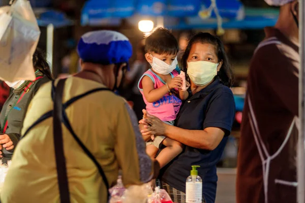 Koh Samui, Tayland - 30 Mart 2020: sokak satıcıları çalışmaya devam ediyor, küçük çocuk ailesiyle yiyecek almaya geliyor. Önlemler alındı: el dezenfektanı, satıcıların maskeleri ve onların küçük müşterileri ve anneleri..