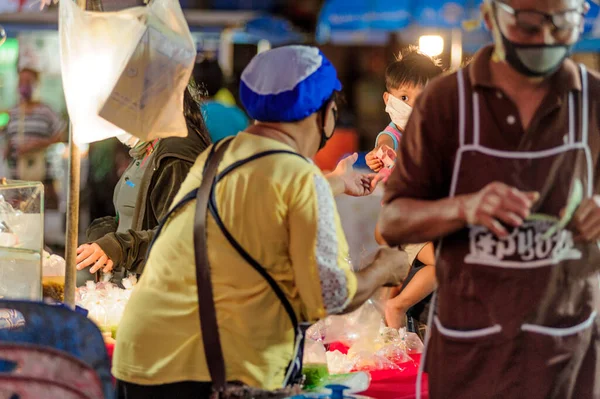 Koh Samui, Tayland - 30 Mart 2020: sokak satıcıları çalışmaya devam ediyor, küçük çocuk ailesiyle yiyecek almaya geliyor. Önlemler alındı: el dezenfektanı, satıcıların maskeleri ve onların küçük müşterileri ve anneleri..