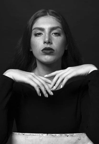 Black and white portrait of a sad girl dressed in black blouse.