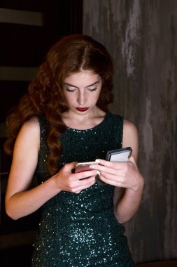 Genç güzel kız smartphone telefon içine arıyorum. yeşil elbise ve uzun kızıl saçlı saçlı ince kız. O telefon vasıl aşağı görünüyor.