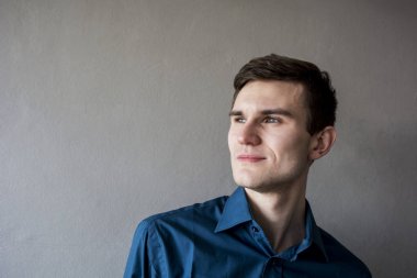 Uzak seyir yakışıklı bir adam portresi. Bir yeşil gömlek. Esmer yeşil gözlü. Bir tek sesli gri arka plan üzerinde. Hafifçe gülümsüyor. Adam hayal. 