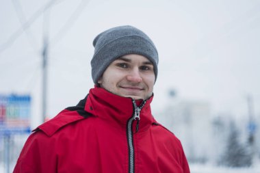 Kırmızı bir ceket ve gri bir yakışıklı bir adam. Yeşil gözlü genç bir adam. Mutlu bir erkek gülümseyen ve kameraya bakıyor. Beyaz zemin üzerinde bir adam portresi.