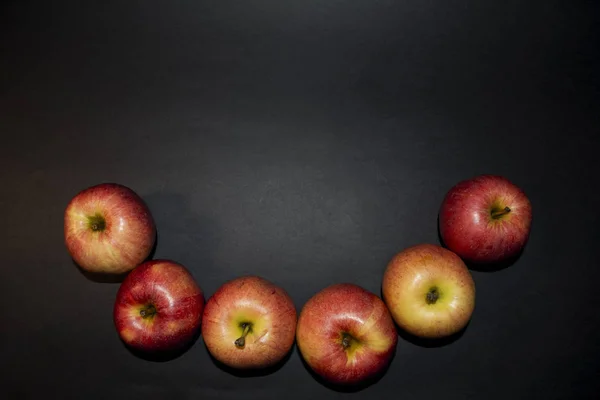 Red juicy apples. On a black background. In a warm tube light. Beautiful apples are ideal shape. — Stock Photo, Image