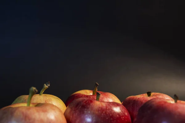 Red juicy apples. On a black background. In a warm tube light. Beautiful apples are ideal shape. — Stock Photo, Image