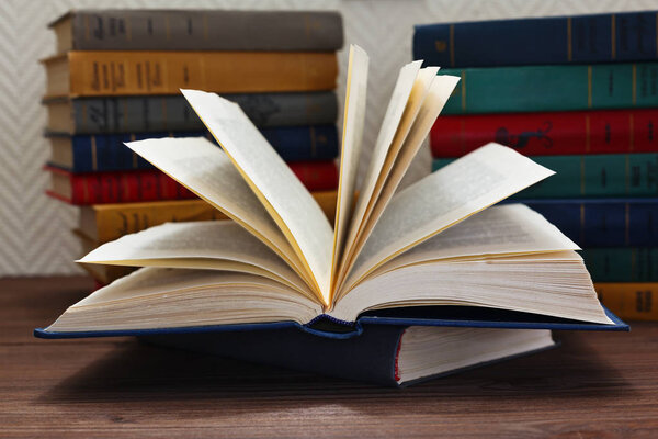 Opened book in front of stack of books