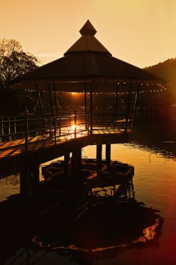 Gün batımı ışığında bir gölet üzerinde Pavilion
