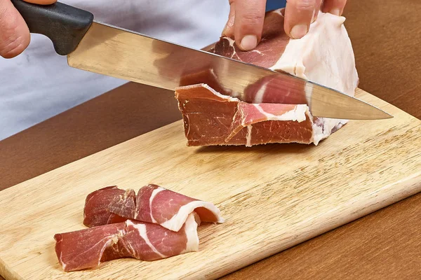 Dry cured ham thinly sliced Closeup on chef hands slices prosciutto Italian delicatessen
