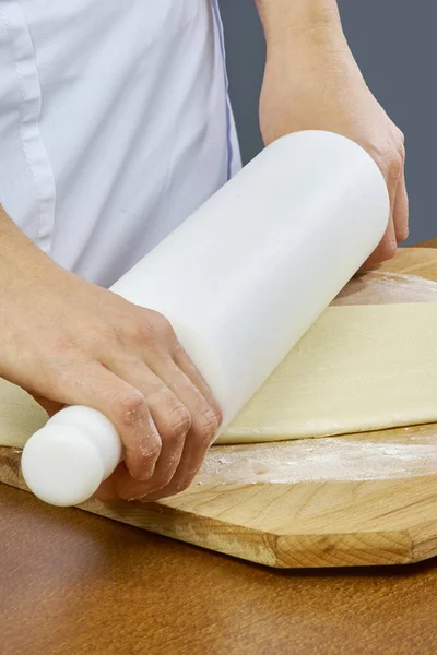 Stendere l'impasto Primo piano mano dello chef panettiere in uniforme grembiule blu cuocere la pizza in cucina collezione completa di ricette — Foto Stock
