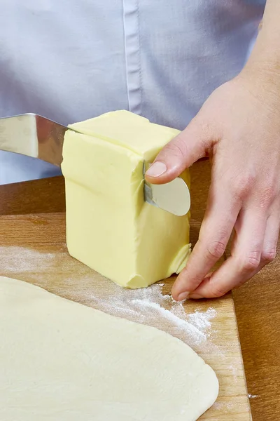 シェフが生地準備チーズケーキ シリーズ完全調理料理のレシピに広がるバターの大きな部分をカットします。 — ストック写真