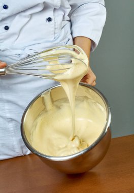 Şef cheesecakes yapmak için el ile bir kase sarı krem kamçı