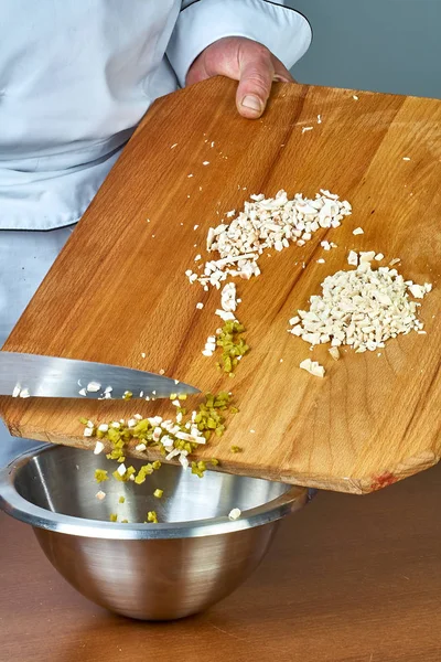 El cocinero vierte los ingredientes cortados en un tazón lleno de recetas para recetas de alimentos — Foto de Stock