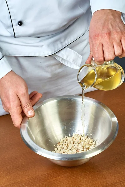 El cocinero vierte aceite de oliva en un tazón lleno de recetas para la comida — Foto de Stock