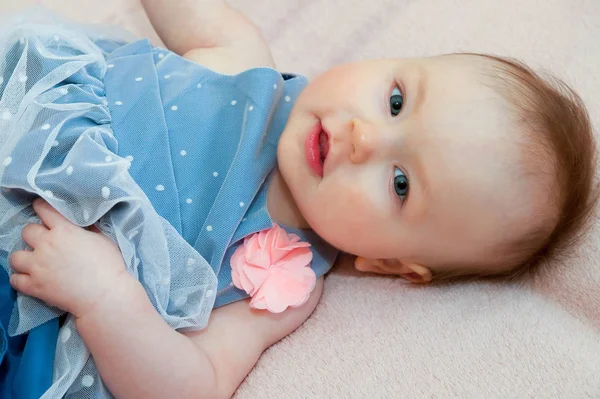 Cute dziewczynka w niebieskiej sukience z różowy kwiat — Zdjęcie stockowe