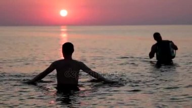 Suya günbatımı arka plan üzerinde bir deniz üzerinde giden bir adam silüeti. Gün batımına doğru gidiyor