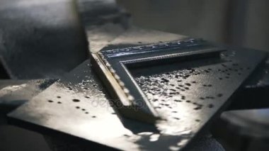 Marangoz siyah boya ile bir çerçevesinin bir köşesini boyuyor. Yakın çekim.